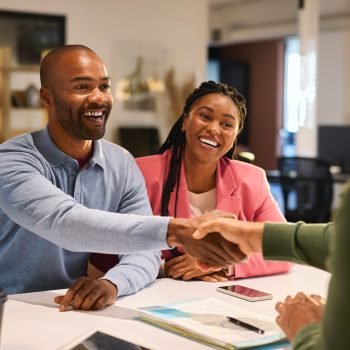 Businessman handshake with black couple during meeting to protect their investments. Handshake of a manager with young couple after agreement for financial investment. Happy financial advisor shaking hands with his client after insurance deal.